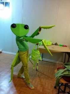 a person dressed as a green alien holding a bug in one hand and an insect in the other