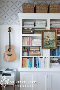 a bookshelf filled with lots of books next to a wall mounted ukule