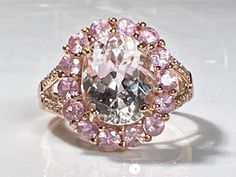 a fancy ring with pink and white stones in it's center, set on a marble surface