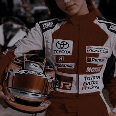 a woman in a racing suit holding a helmet