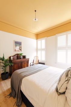 a bed sitting in a bedroom next to two windows