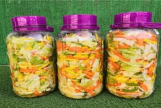 three mason jars filled with different types of veggies sitting on the ground next to each other