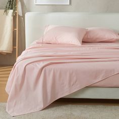 a bed with pink sheets and pillows on it