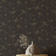 a vase sitting on top of a wooden table next to a wallpaper covered in flowers