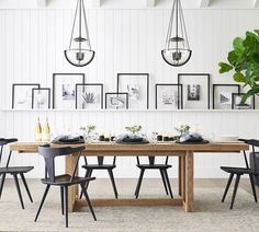 a dining room table with chairs and pictures on the wall behind it in black frames