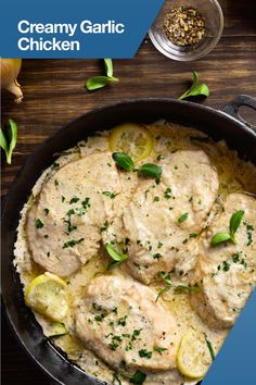 creamy garlic chicken in a skillet with lemons and herbs on the side for garnish