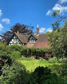 a large house surrounded by lush green trees and bushes on a sunny day with blue sky in the background