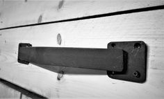 a black and white photo of a metal handle on a wooden door with planks in the background