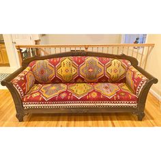 an ornately decorated couch sitting on top of a wooden floor next to a bannister