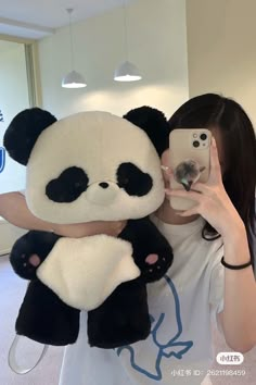 a woman taking a selfie with her cell phone while holding a stuffed panda bear