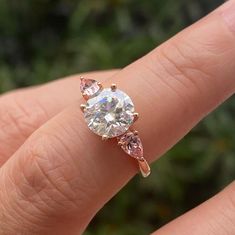 a person's hand holding a ring with two stones on it and the middle finger