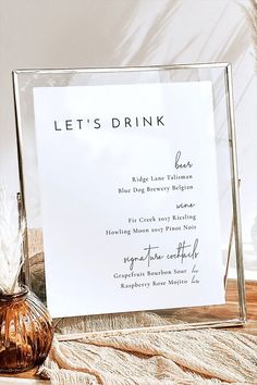 there is a sign that says let's drink in front of a glass vase