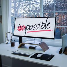 a computer screen with the word impossible written on it sitting on a desk next to a laptop