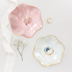 two pink and white dishes with gold trimmings next to each other on a white surface