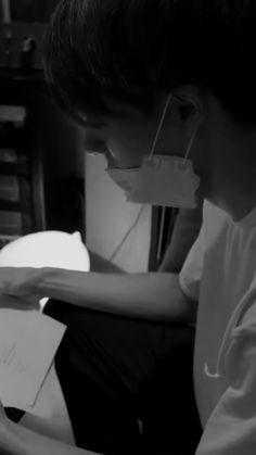 a young man sitting on the floor with papers in front of him and an eye mask over his mouth