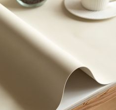 a cup and saucer sitting on top of a table next to a white wall