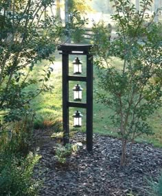 an outdoor lantern stand in the middle of a field with trees and grass behind it