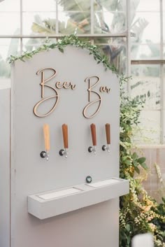 the beer tap sign is decorated with greenery and wooden pegs to hang on the wall