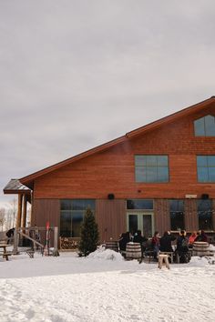 a group of people sitting outside of a building in the snow with a dog standing next to them