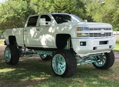 a large white truck parked on top of a lush green field