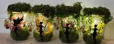 four jars filled with plants and fairy figurines