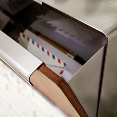 a close up view of an oven door with mail in the drawer and a wooden handle