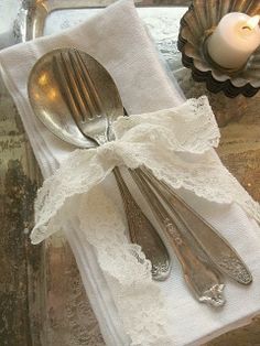 two silverware are sitting on top of a white napkin with a bow around it