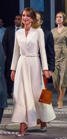 queen letizia of spain is wearing a white coat and matching shoes as she walks down the street