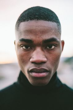 a close up of a person wearing a black turtle neck shirt and looking at the camera