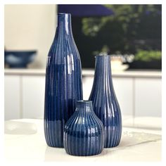 three blue vases sitting on top of a white table