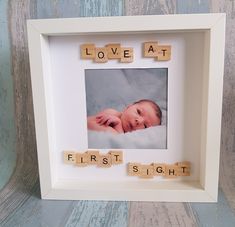 a baby's first sight spelled with scrabbles in a white frame