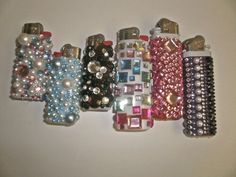 a group of different colored and shaped cell phones on a white surface with pearls attached to them