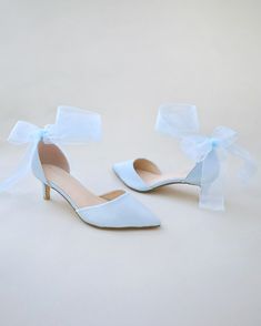 a pair of white high heeled shoes with bows