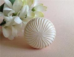 a white vase with flowers on it next to a pink background and the image is in focus