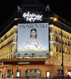 a large advertisement on the side of a building in front of a traffic light at night