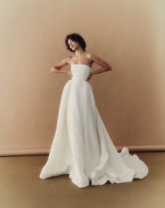 a woman in a white dress posing for the camera with her hands on her hips