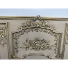 an ornate white and gold painted bed frame