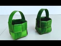 two green baskets sitting on top of a white table next to each other and one is made out of bamboo