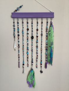 a wall hanging with beads and feathers on it