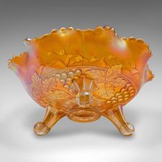 an orange glass bowl sitting on top of a stand