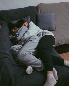 a man laying on top of a black couch