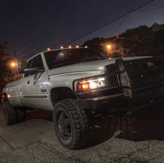 the truck is parked on the side of the road at night with its lights on