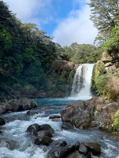 there is a waterfall in the middle of this river with rocks and trees around it