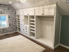 an empty room with white cabinets and carpeted flooring in front of a window