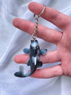 a hand holding a keychain with a fish on it