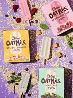 three different flavors of oatmik ice cream on a purple surface with cereal scattered around them