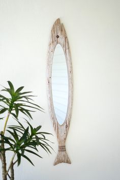 a wooden mirror hanging on the wall next to a potted plant in front of it