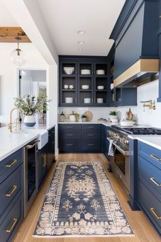 a kitchen with blue cabinets and an area rug on the floor in front of it