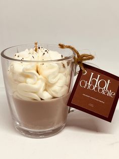 a glass cup filled with marshmallows on top of a white table next to a tag