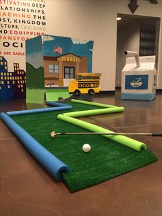 an indoor golf course with balls and tees on the ground